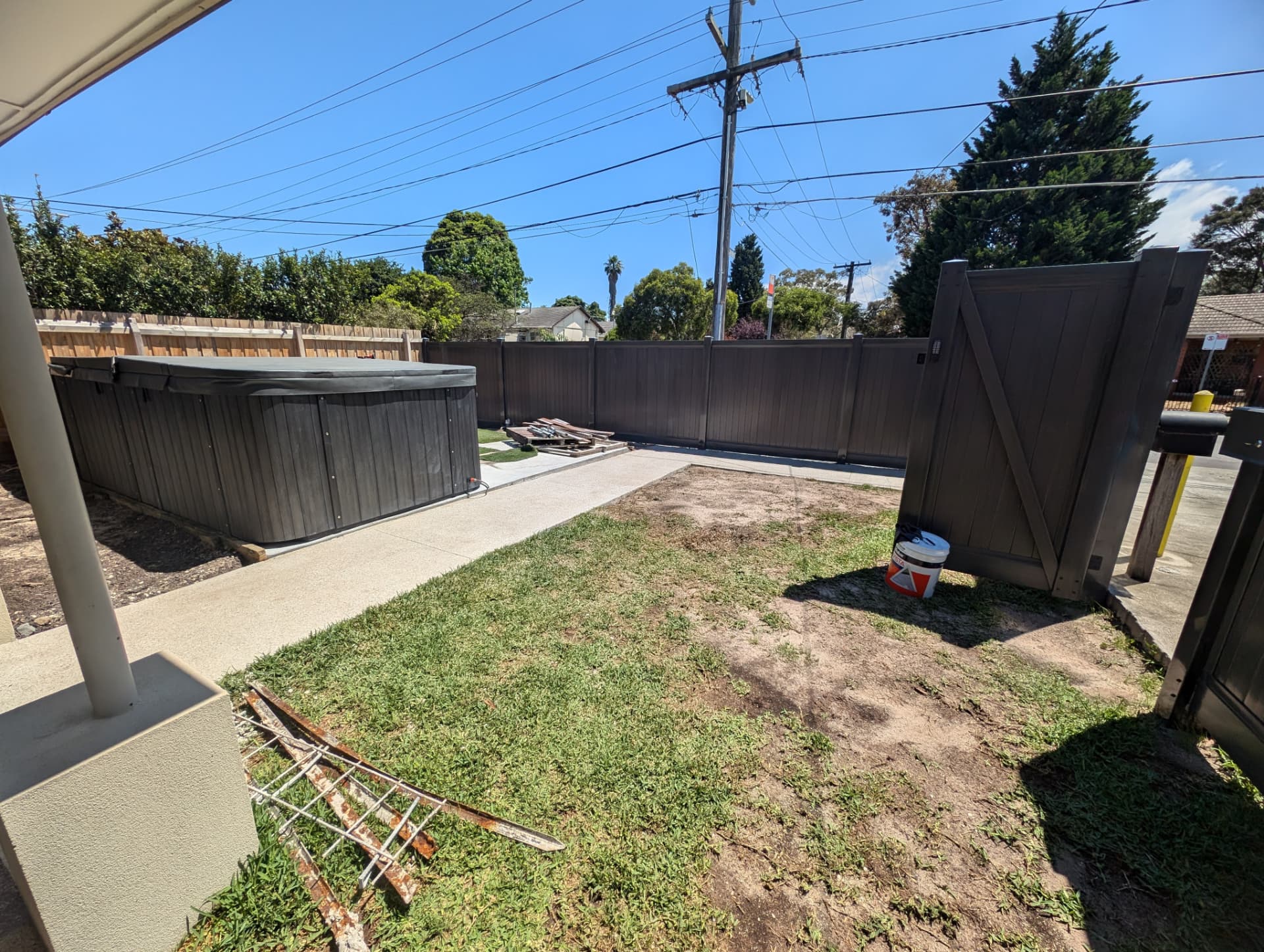 Dark composite privacy fence and gate with concrete path alongside
